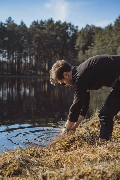 man on the lake, washes his hands, makes spray, rest in the woods on nature.