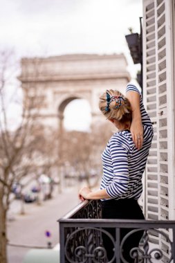Sabahları Paris 'te balkonda çekici genç bir kadın.