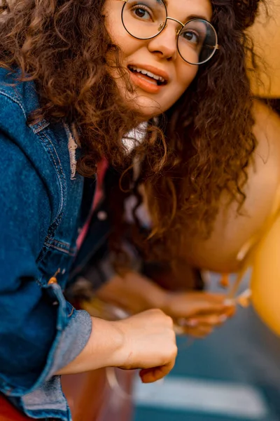 Balonlu güzel kıvırcık kız. Balonlu bir arabada cadde boyunca gezen mutlu bir kadın. Yaz batımı.