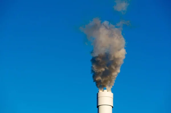 Загрязненный дым над чистым голубым небом из высокого дымохода — стоковое фото