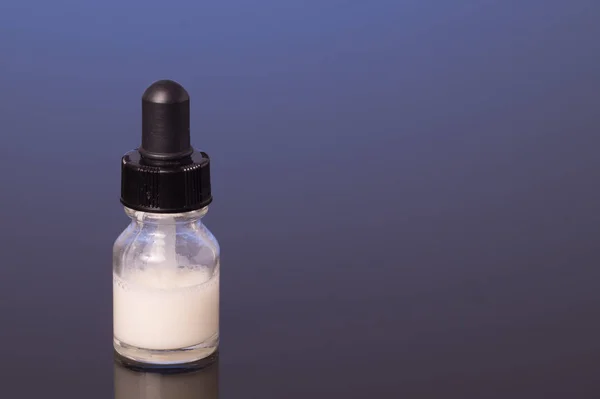 Druppelaar fles met melk witte vloeistof — Stockfoto