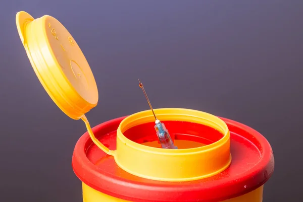 Gelbe medizinische Entsorgungsbox, Spritzennadel mit rotem Tropfen auf der Spitze — Stockfoto