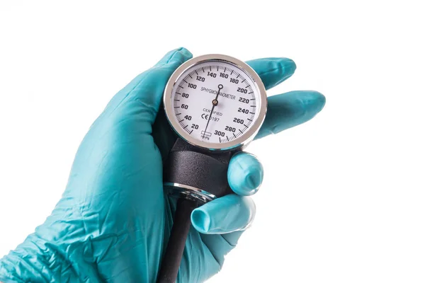 Mão com luva de proteção verde segurando um medidor de pressão arterial — Fotografia de Stock