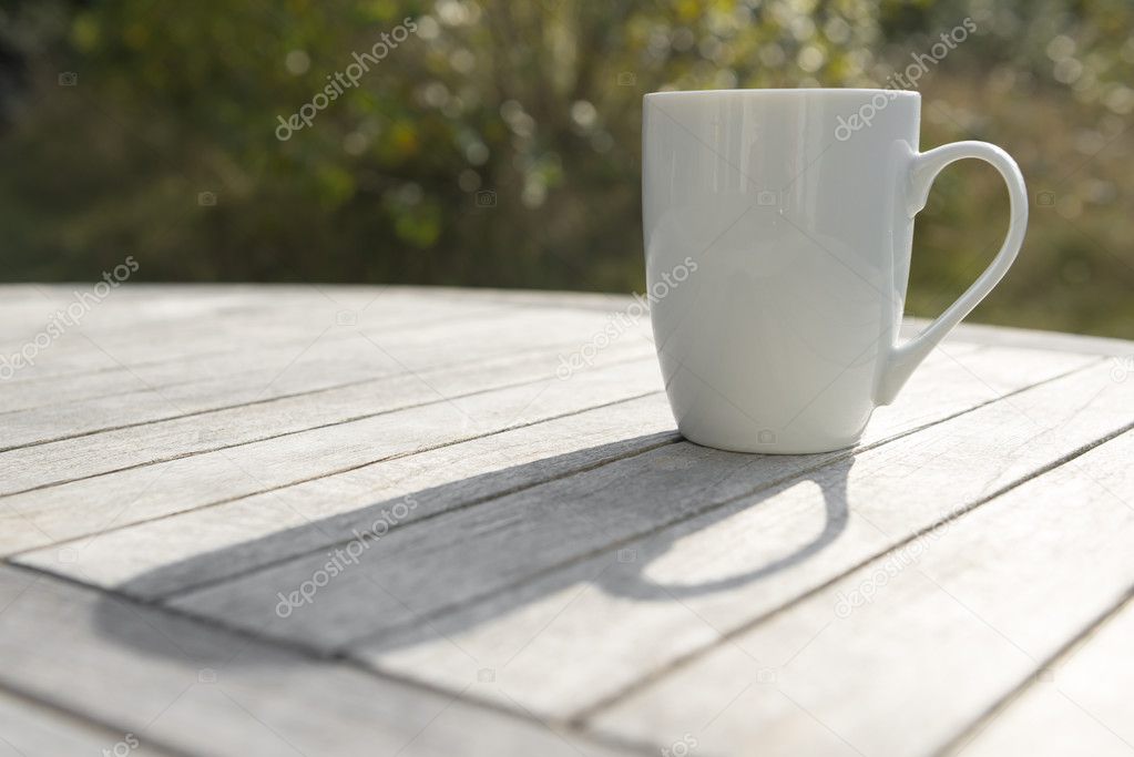 Drinking cup on a wooden table in the Sun