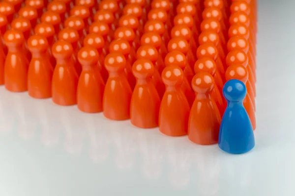 Концептуальні оранжеві ігрові пішаки і синій пішак — стокове фото