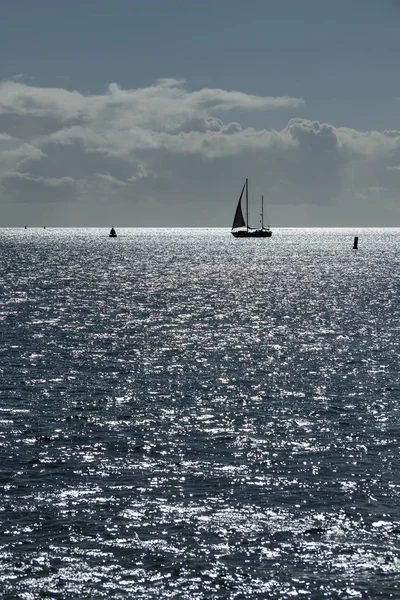 Segelboot gegen den grellen Schein der Sonne im Meer — Stockfoto