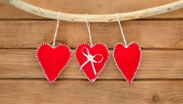 Romantic love composition of red felt hearts on wooden background — Stock Photo, Image