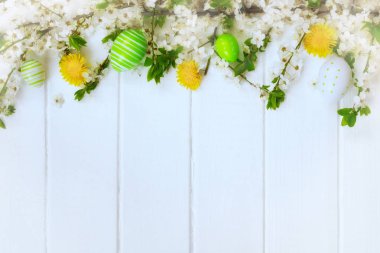 Paskalya süslemeleri, bahar çiçekleri ve beyaz tahtalarda yumurtalar..