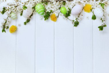 Paskalya süslemeleri, bahar çiçekleri ve beyaz tahtalarda yumurtalar..