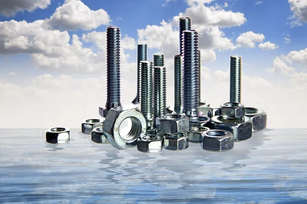 Болты и гайки строят город, стоя, как небоскреб, между голубым небом и морем — стоковое фото