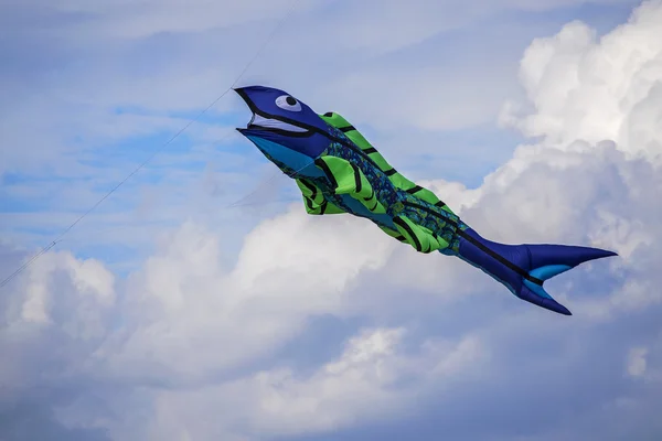 Aquilone di pesce blu e verde che vola nel vento contro il cielo con le nuvole — Foto Stock