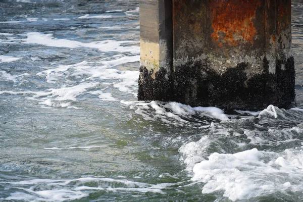 Rusty pier with shells in the spray from the sea, abstract port background