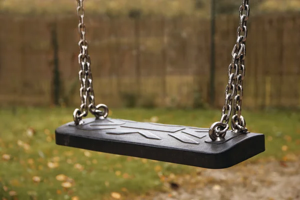 Niños vacíos se balancean en cadenas en un jardín otoñal, concepto de pérdida —  Fotos de Stock