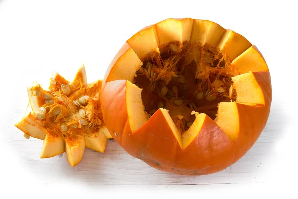 Zucca arancione tagliata aperta con frutta e semi su legno verniciato bianco — Foto Stock