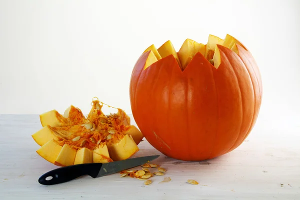 Calabaza naranja fresca cortada abierta con tapa y cuchillo sobre madera pintada de blanco —  Fotos de Stock