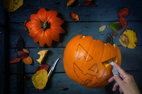 Een pompoen snijden voor halloween of herfst decoratie op blauwe rusti — Stockfoto