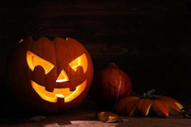 Oyma halloween kabak koyu renkli rustik ahşap bir sonbahar dekorasyon olarak korkutucu bir parlayan yüz ile
