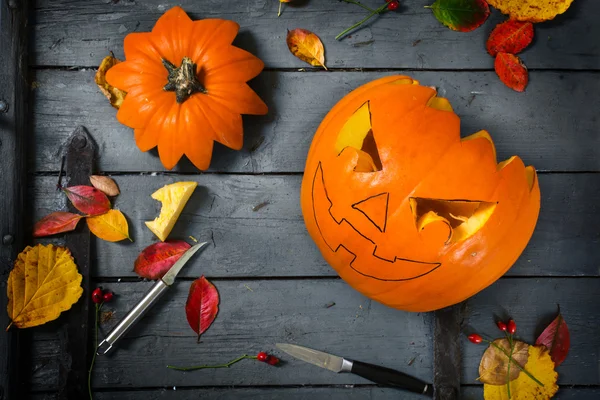 Préparation d'une citrouille sculptée pour Halloween, décoration d'automne bricolage sur une table en bois rustique gris — Photo