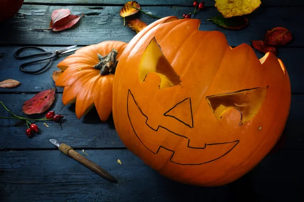 Carving een pompoen voor halloween, herfst decoratie op een blauwe rustieke houten tafel ketellapper — Stockfoto