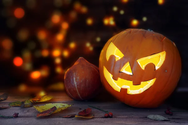 Gesneden halloween pompoen met een gloeiende eng gezicht, donkere achtergrond met wazig lights — Stockfoto