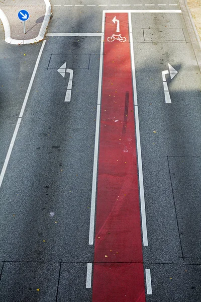 Велосипедна смуга з червоним маркуванням і велосипедним символом на асфальтній дорозі з спрямованими стрілками — стокове фото