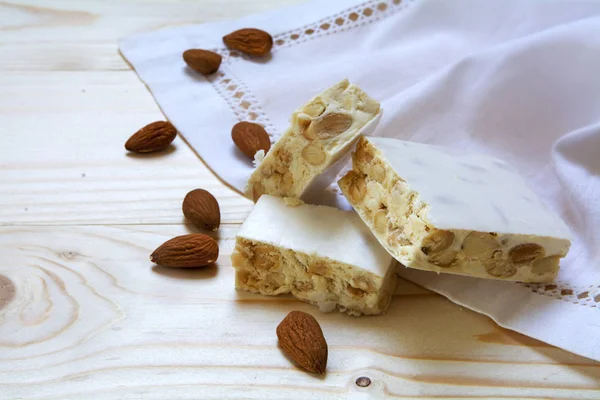 Torrone or white nougat with almonds and napkin on a wooden table, traditional for christmas — Stock Photo, Image