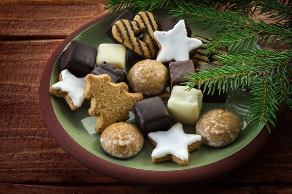 Christmas cookies and fir branches, plate full of traditional gingerbread cakes, cinnamon stars and pepper nuts