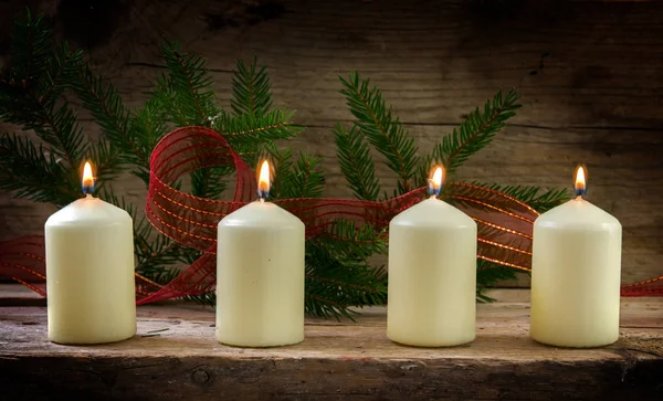 Cuatro velas blancas ardientes en el cuarto advenimiento, decoración de Navidad en un tablero rústico de madera —  Fotos de Stock