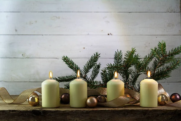 Quatro velas brancas acesas no quarto advento, decoração de Natal em uma tábua de madeira rústica contra madeira branca com espaço de cópia — Fotografia de Stock