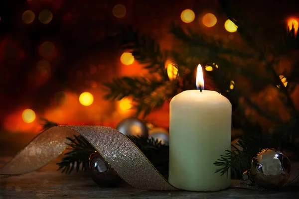 Белая горящая свеча с рождественским декором на деревенском деревянном столе, темно-теплый фон с боке огней — стоковое фото