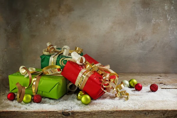 Weihnachts- und Neujahrsgeschenke aus grünem und rotem Papier, goldene Schleifen und Kugeln auf rustikalem Holzbrett, Vintage-Hintergrund — Stockfoto