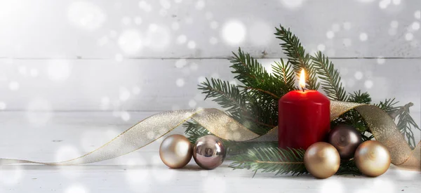 Bougie brûlante rouge avec décoration de Noël, sapin, boules et ruban doré, devant un mur en bois blanc avec des lumières bokeh — Photo