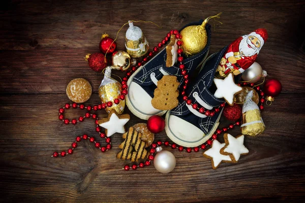 お菓子と 12 月 6 日、ニコラスの日の赤いクリスマスの飾りでいっぱいの子供の靴 — ストック写真