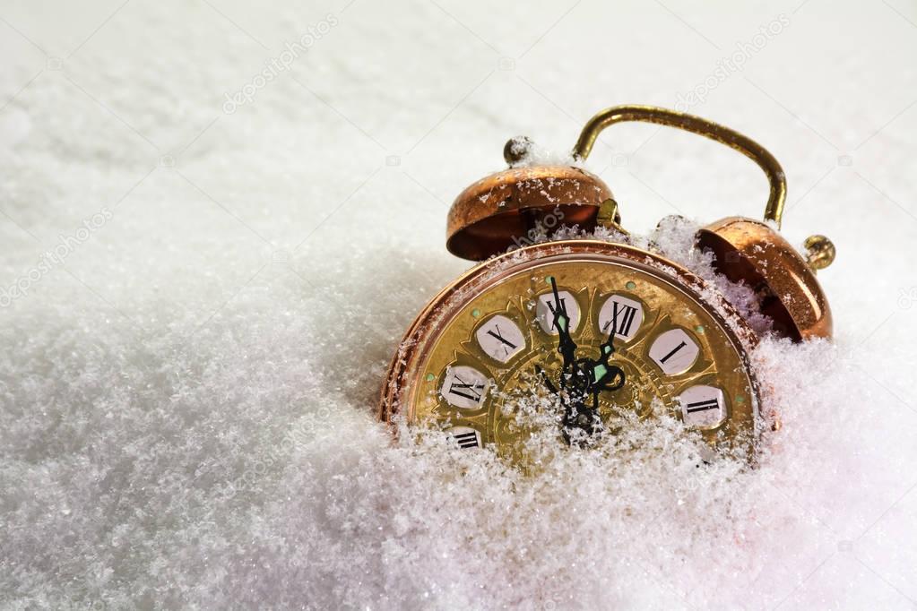 Vintage alarm clock in the snow shows five minutes before twelve, concept for new year