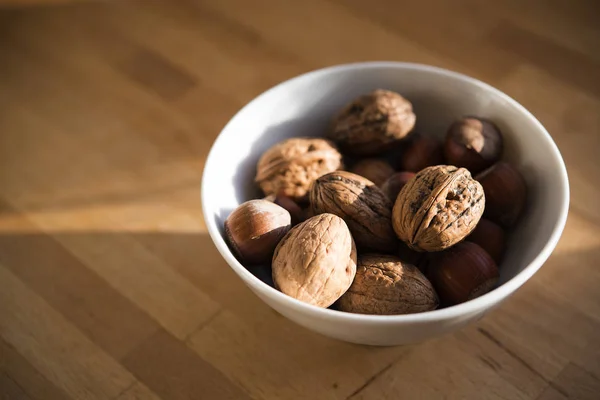 Nueces frescas en un tazón blanco sobre una mesa de madera, espacio para copiar — Foto de Stock