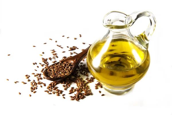 Brown flax seeds on a spoon and linseed oil in a glass jug isolated on a white background — Stock Photo, Image