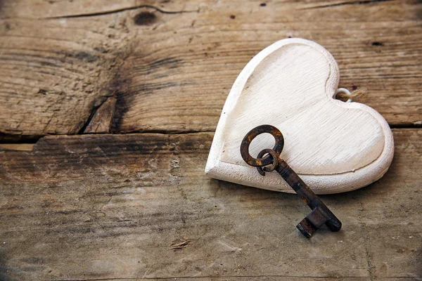 Forma de coração feito de madeira pintada de branco e uma chave velha em rústico — Fotografia de Stock