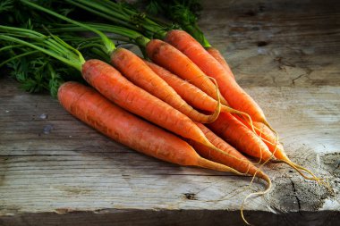 Rustik ahşap bir masa kopya alanı üzerinde yeşil yaprakları ile taze havuç