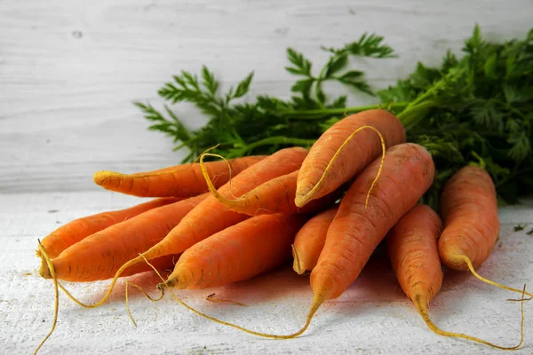 Massa färska morötter med gröna blad på vit målat rustikt trä — Stockfoto