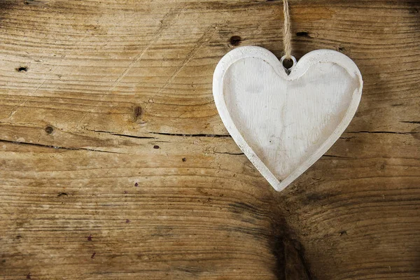 Forma de coração branco feito de madeira pendurada em uma parede de madeira rústica, conceito de amor — Fotografia de Stock