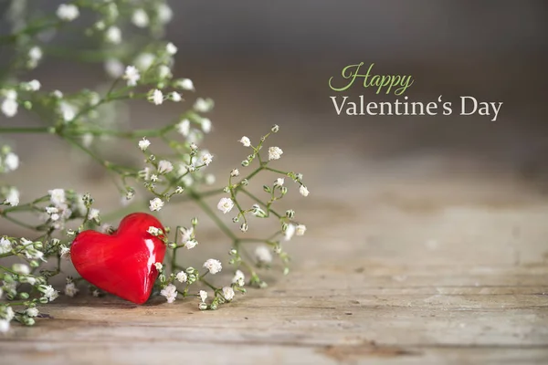 Small red heart from glass and white flowers on a rustic wooden background — Stock Photo, Image