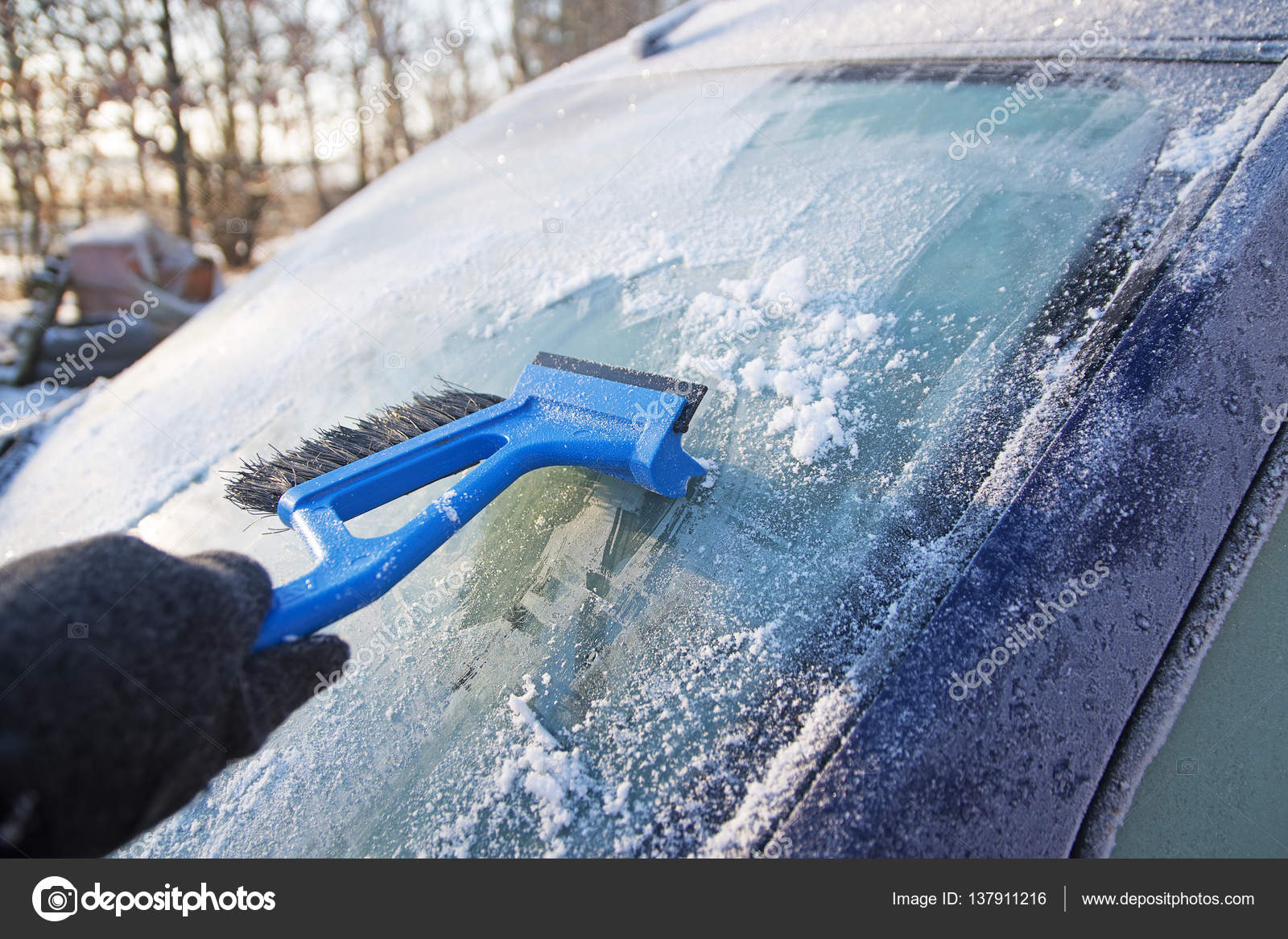 Frozen windshield from a car and a hand scraping the ice with an