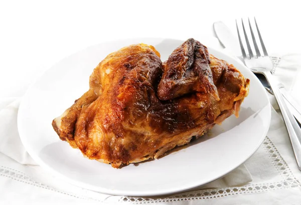 Setengah ayam panggang disajikan di piring, serbet dan peralatan perak, latar belakang memudar menjadi putih — Stok Foto