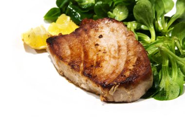 köşe arka plan olarak mısır salatası ve limon parçaları ile kızarmış orkinos biftek