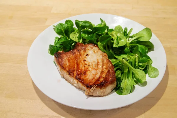 Tonhal steak kukorica saláta egy fehér tányérra egy fából készült háttér — Stock Fotó