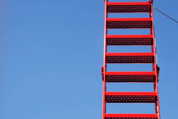 Escalera roja de metal contra el cielo azul, espacio de copia generoso —  Fotos de Stock