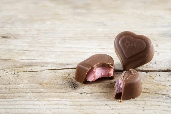 Dos corazones llenos de chocolate, uno roto, sobre madera rústica brillante —  Fotos de Stock