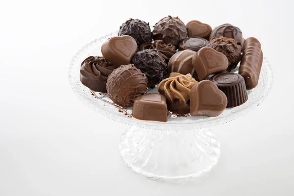 Chocolate praline assortment on a glass plate, against a light gray background — Stock Photo, Image