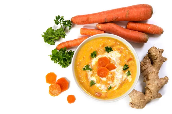 Soupe à la crème de carotte aux ingrédients, racine de gingembre, carottes crues et persil, vue de dessus, isolée sur blanc — Photo