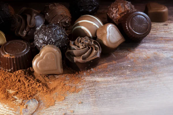 Praline di cioccolato fine su cacao in polvere come regalo d'amore o di vacanza, sfondo angolo su legno rustico — Foto Stock